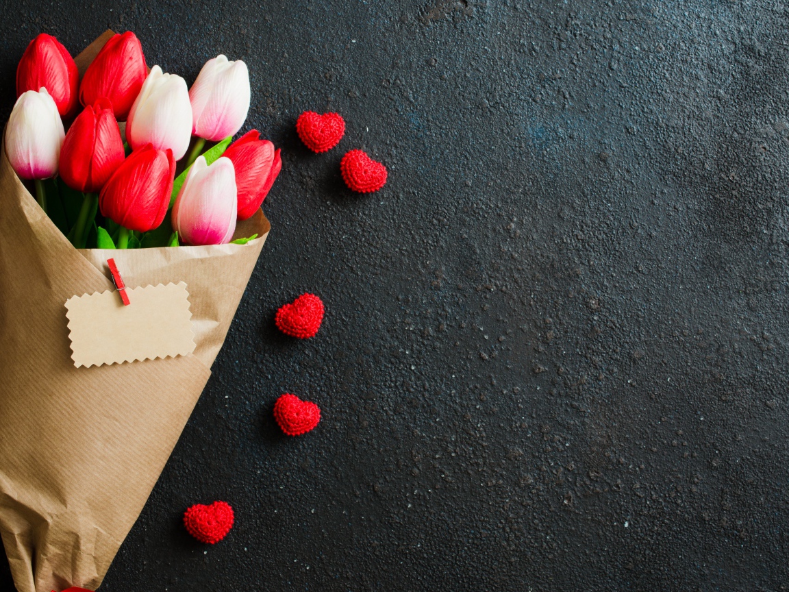 Букет тюльпанов в бумаге на сером фоне с красными сердечками