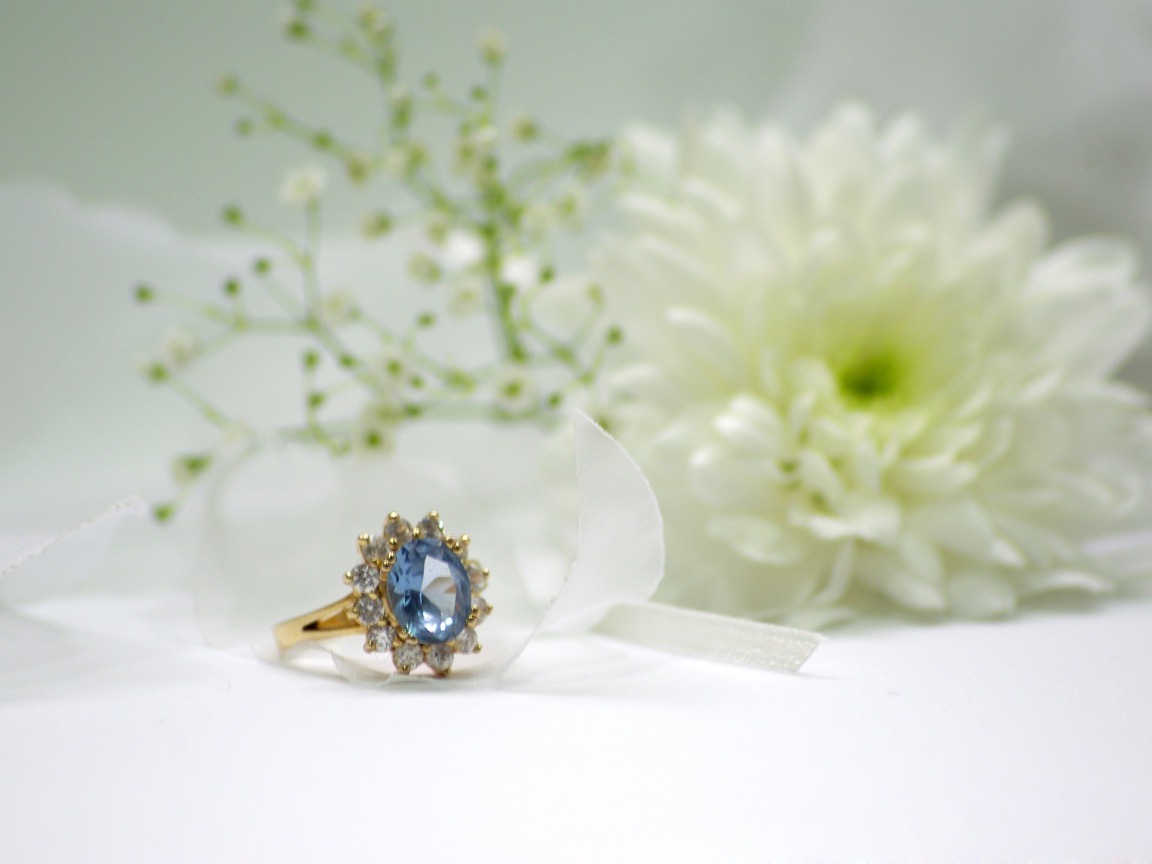 Дорогое кольцо с камнем на столе с белым цветком