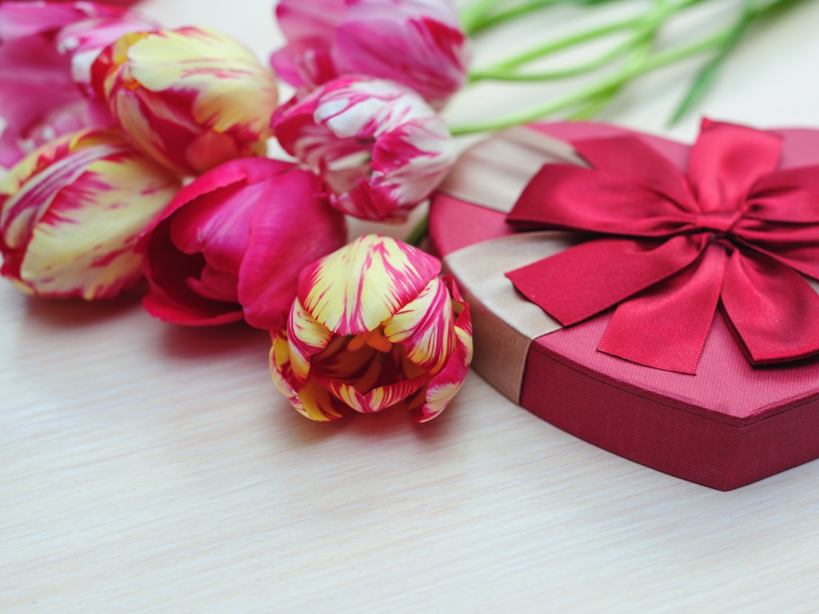 Коробка в форме сердца на столе с букетом тюльпанов