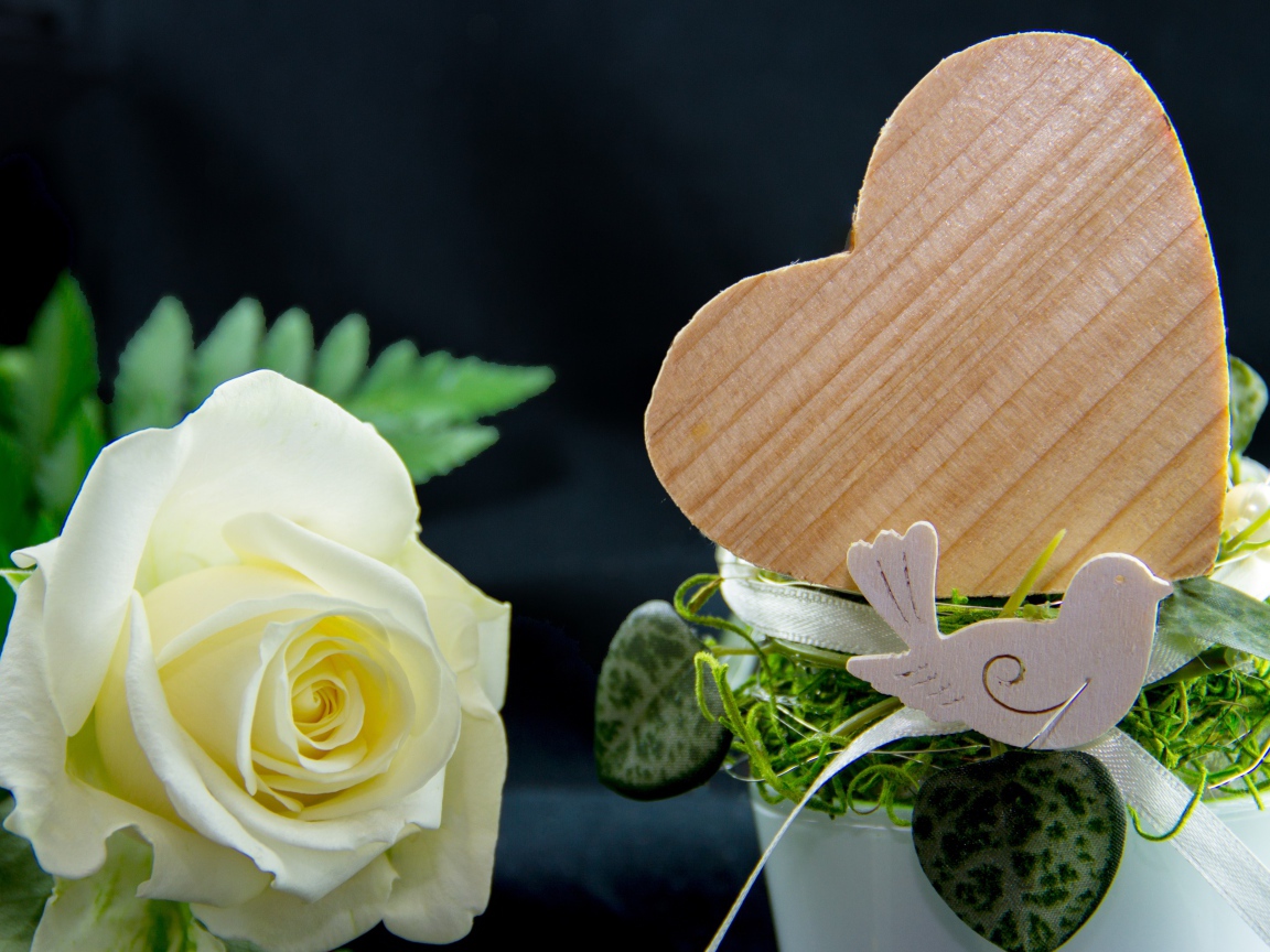 Деревянное сердце и белая роза на столе 