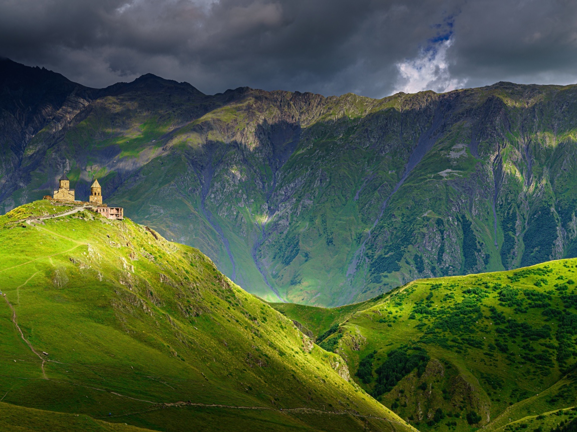 Высокие покрытые зеленой растительностью горы под грозовым небом