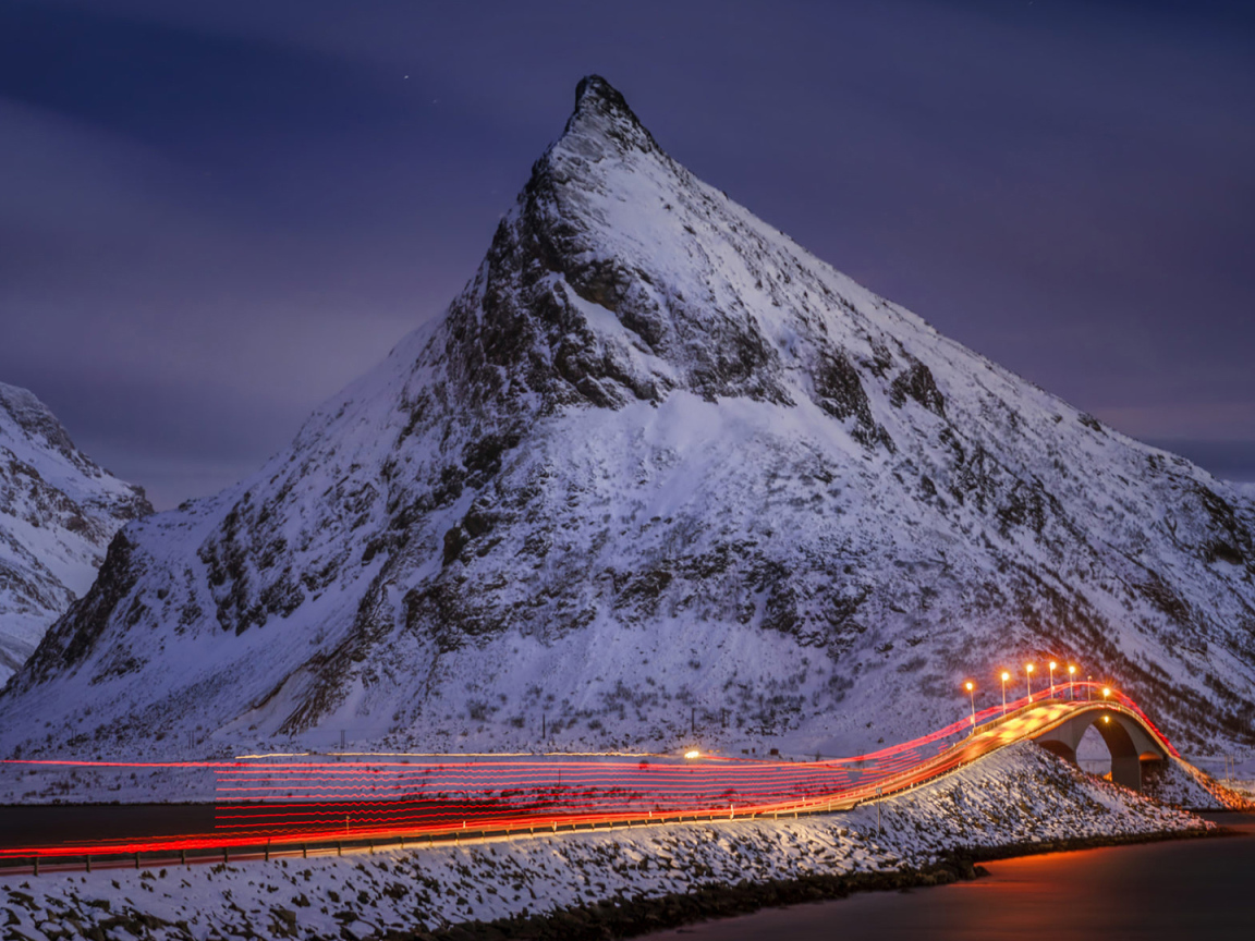Ночная дорога у заснеженных гор 