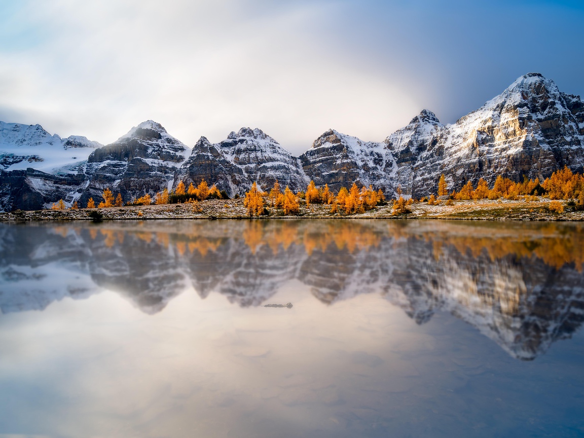Заснеженные горы отражаются в воде озера 
