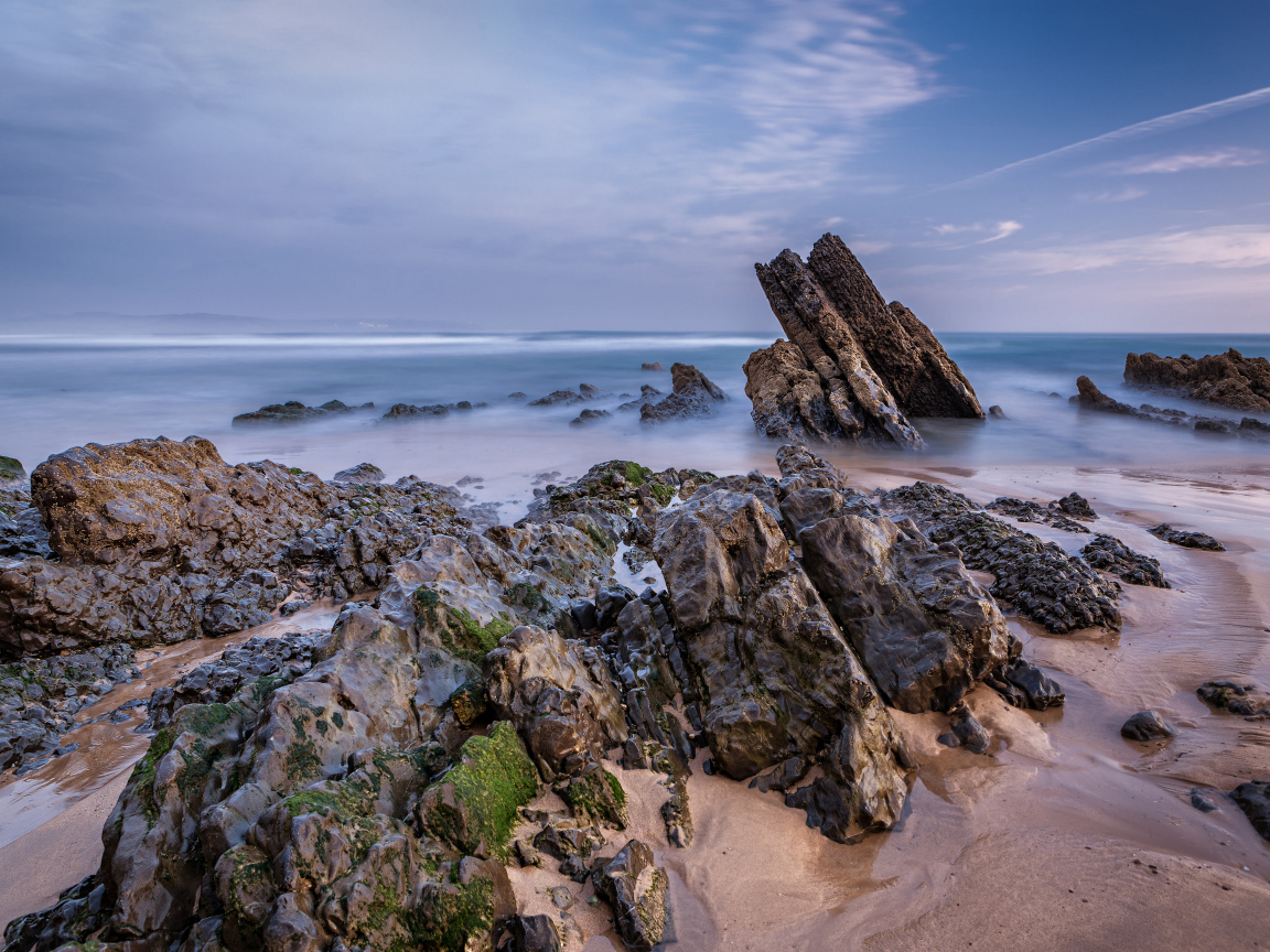 Туман над холодным утренним морем с камнями на берегу 