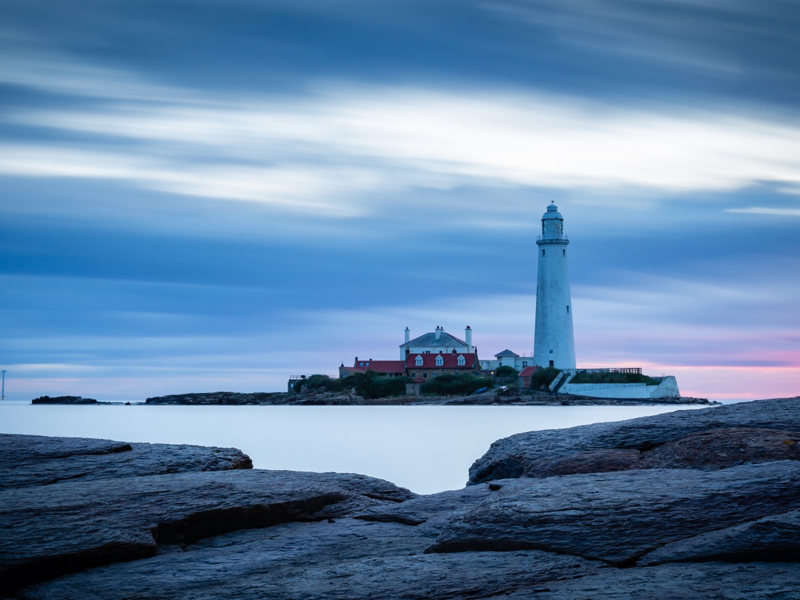 Вид с каменного берега на маяк в море 