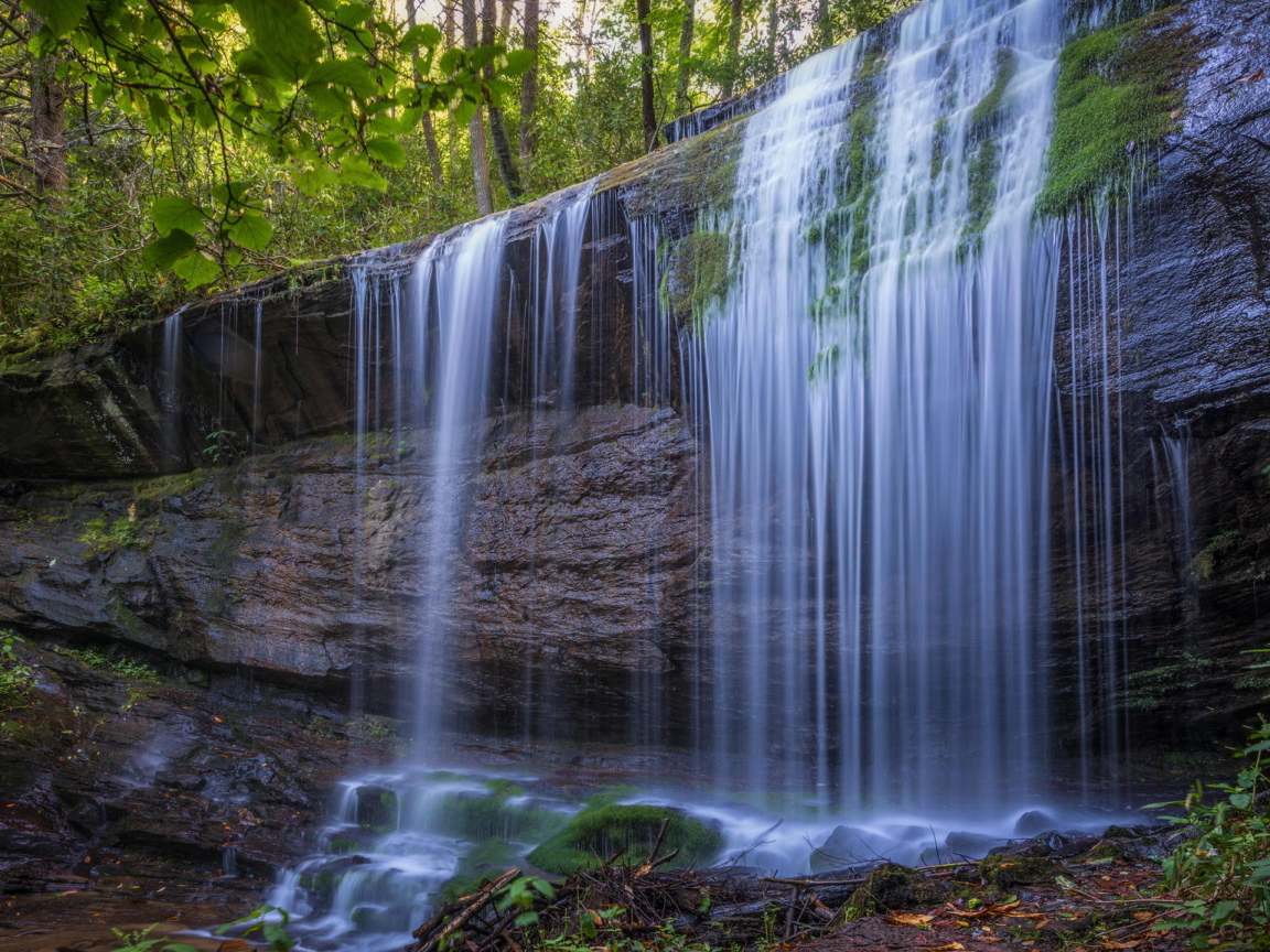 Холодная вода водопада стекает по мокрой скале