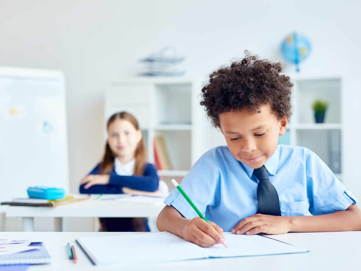 Маленький мальчик сидит за партой в классе