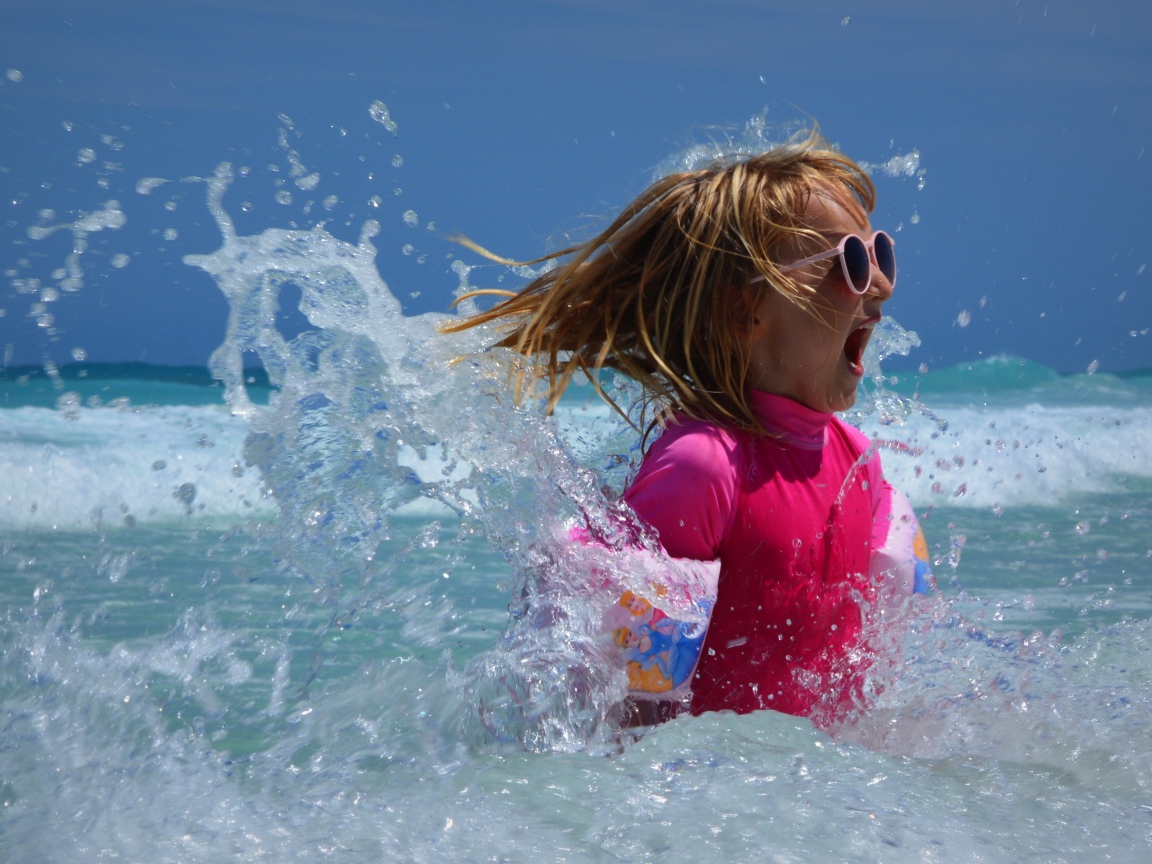 Веселая маленькая девочка купается в море летом