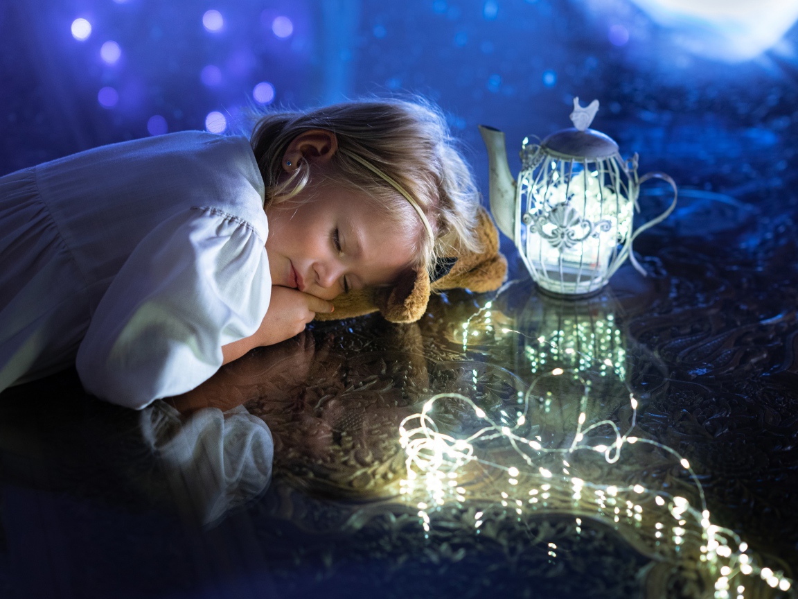 Милая маленькая девочка в белом платье спит на столе