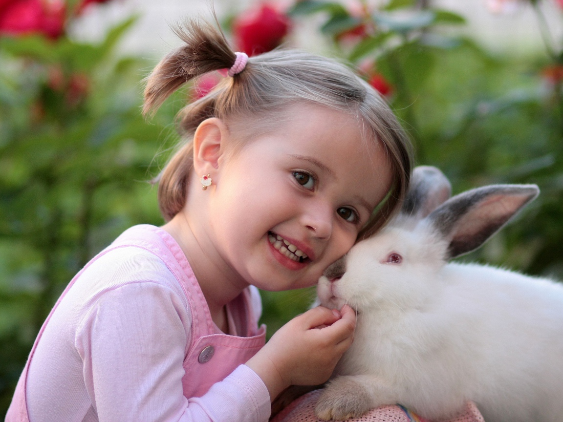 Маленькая улыбающаяся девочка с белым кроликом