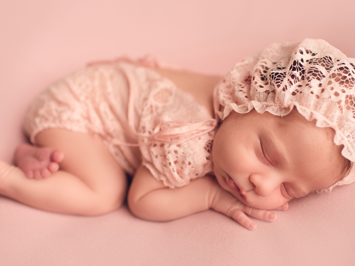 Спящий грудной ребенок в розовом костюме 