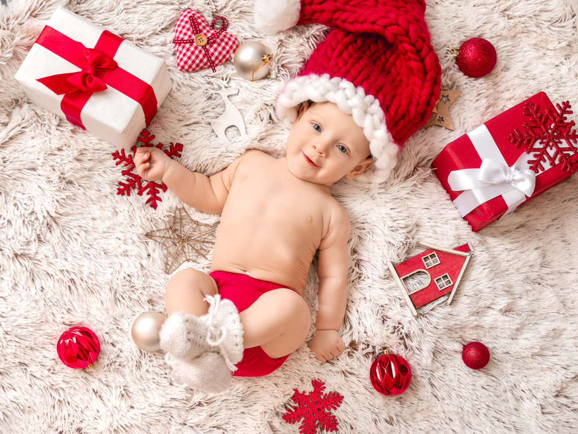 Улыбающийся ребенок  в красной шапке с подарками