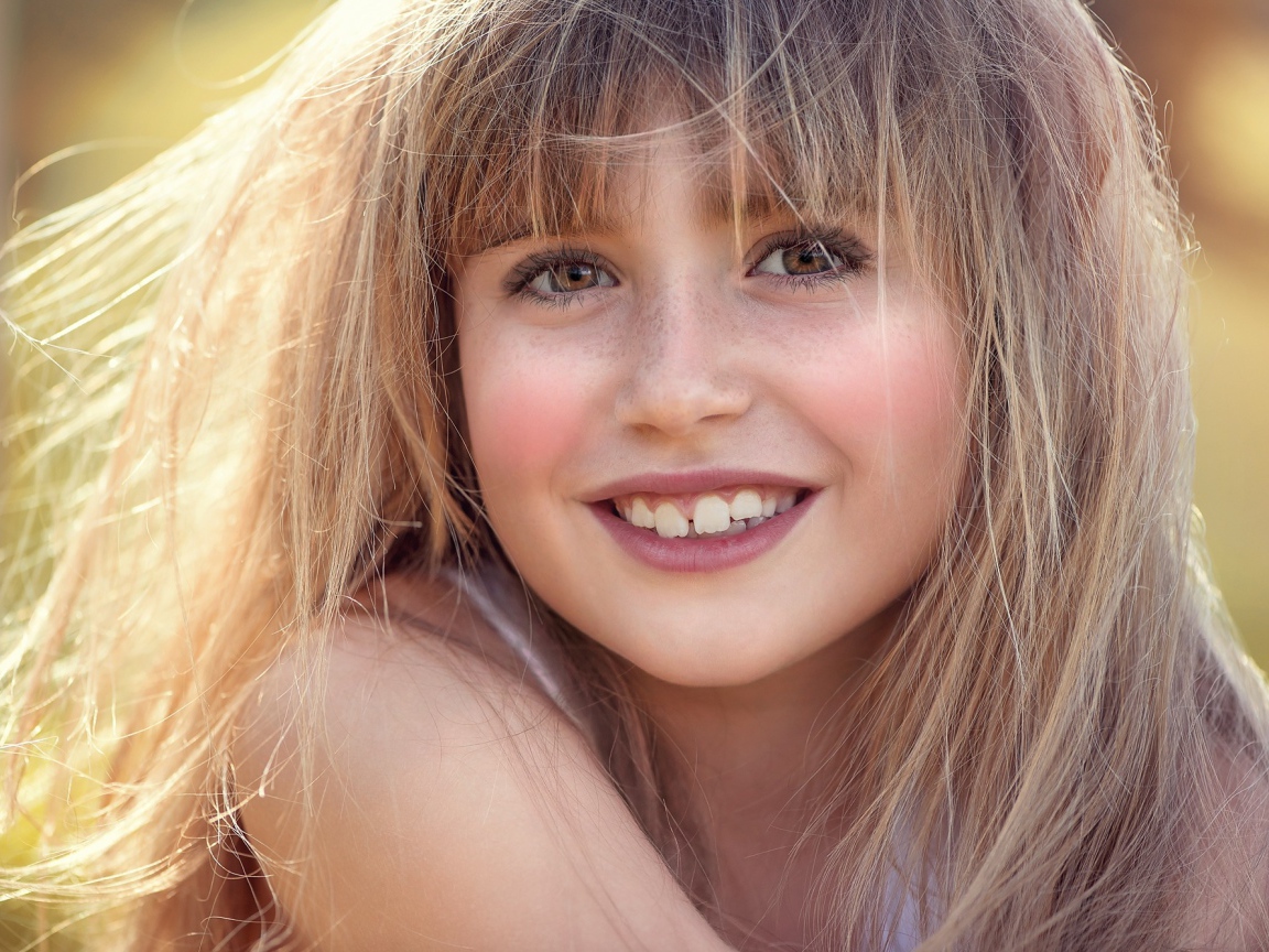 Улыбающаяся девочка с веснушками на лице 