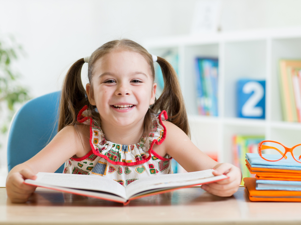 Улыбающаяся маленькая девочка с книгой 