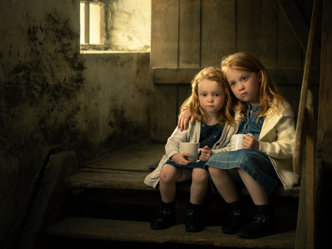 Две маленькие сестры пьют какао на ступеньках дома