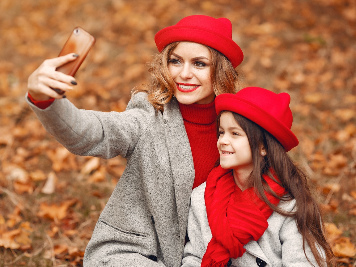 Женщина с маленькой девочкой делают селфи в лесу 