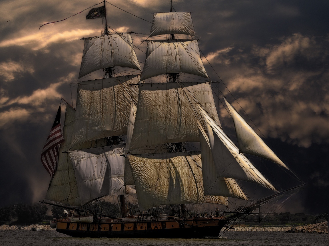 Больше судно с белыми парусами на фоне неба в сумерках 