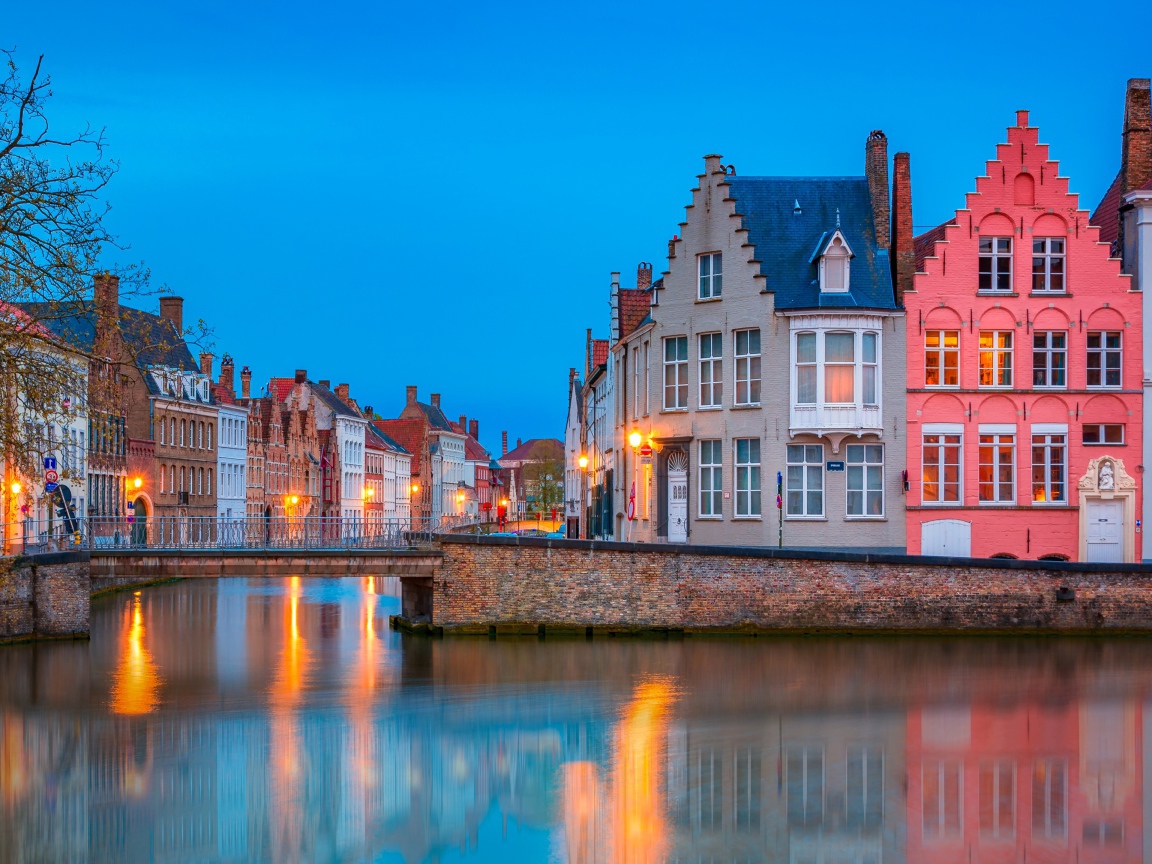 Большие дома и фонари отражаются в воде канала вечером