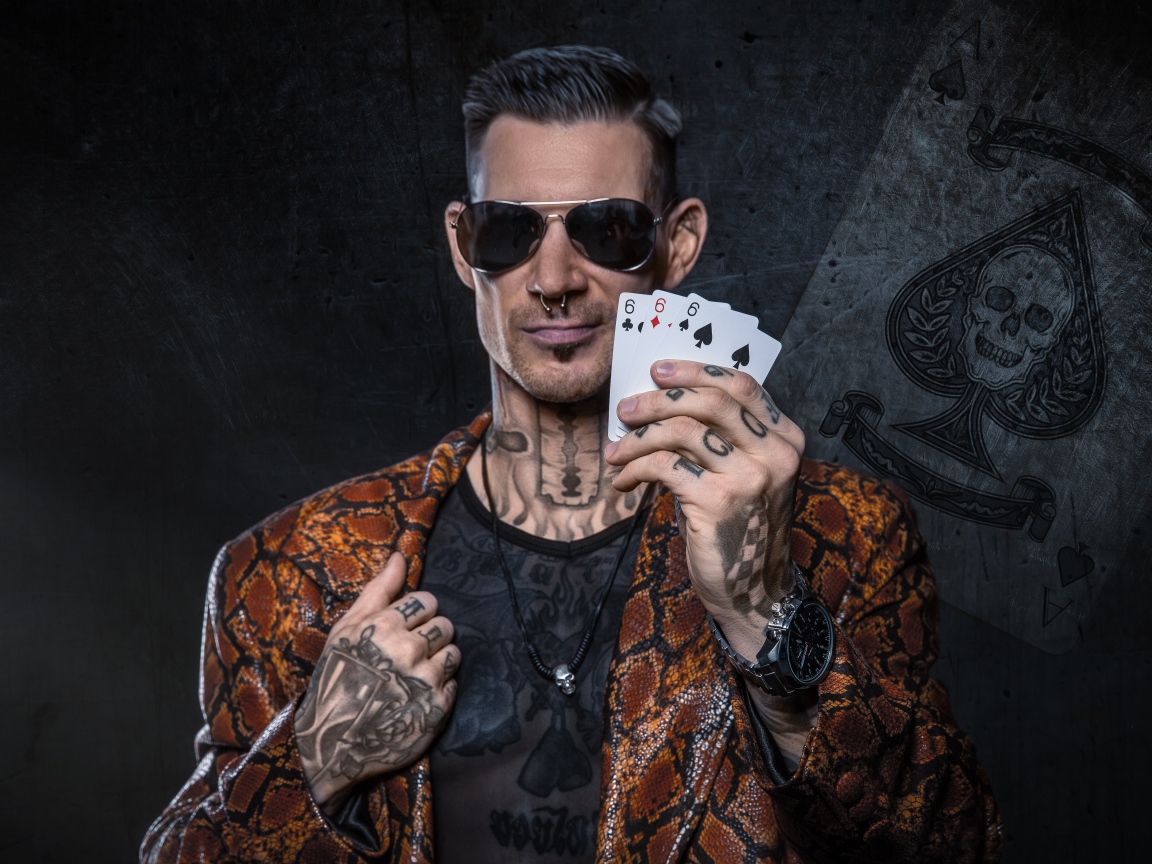 Мужчина с татуировками на теле держит в руке три карты шестерки 
