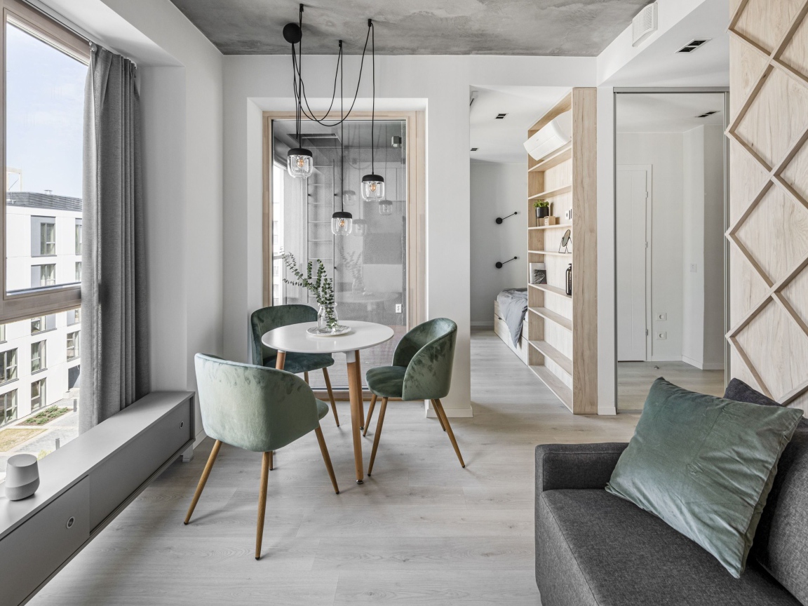 Стол  с креслами стоит у большого окна в квартире 