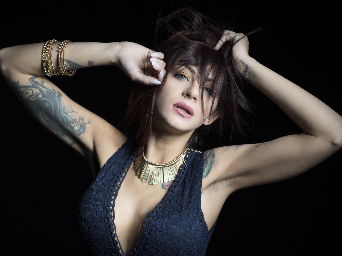 Красивая девушка в черном платье с татуировками на теле 