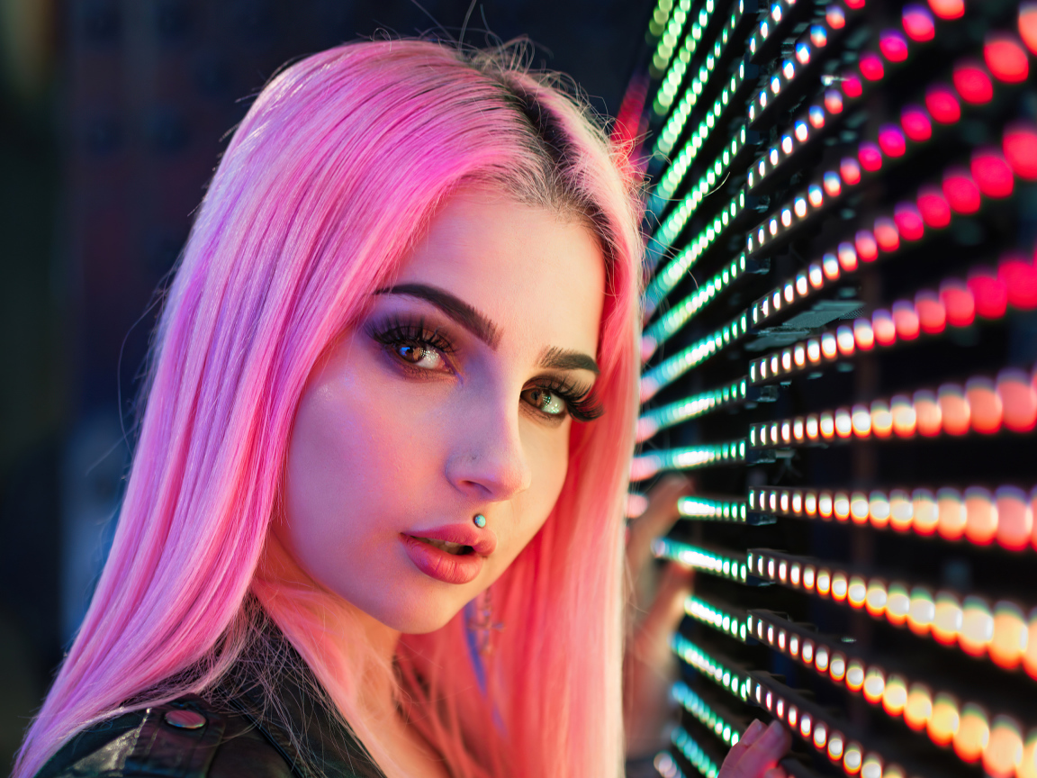 Beautiful girl with pink hair with light bulbs on the wall