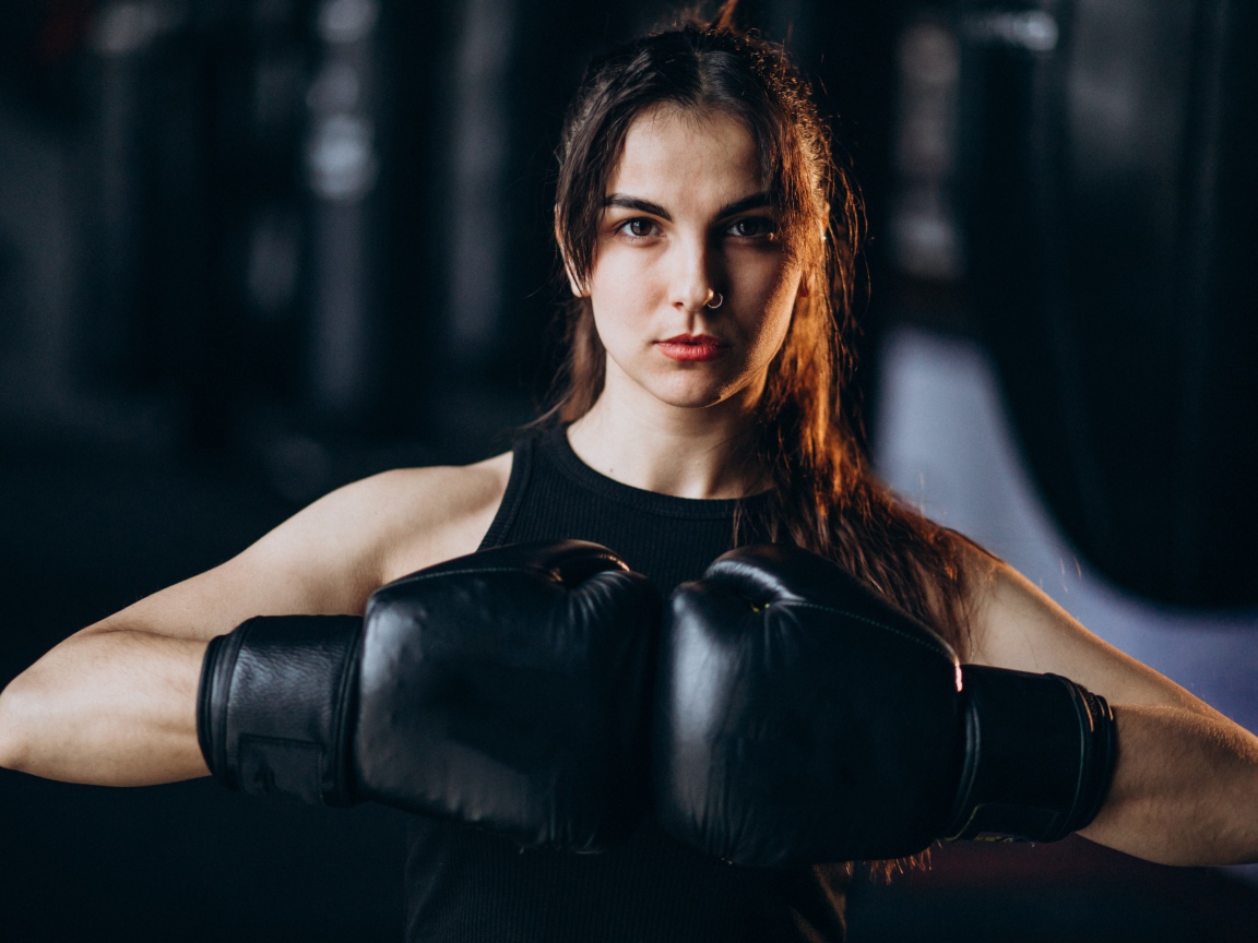 Девушка боксер с черными перчатками на руках 