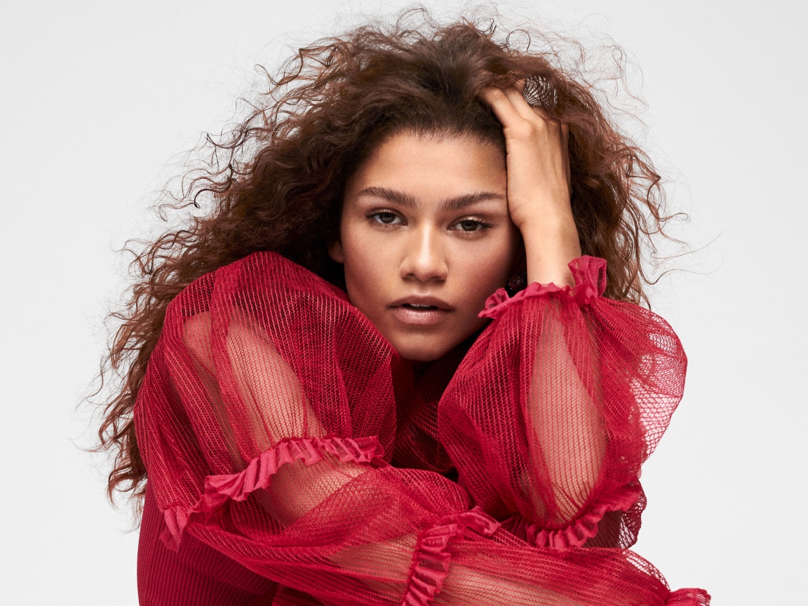 Кареглазая актриса Зендая в красном наряде с рукой в волосах