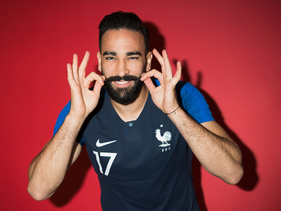 Французский футболист Адиль Рами на красном фоне