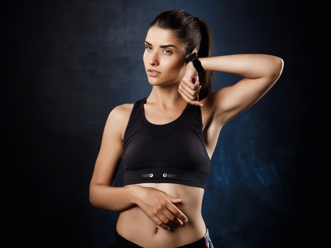 Спортивная девушка в черном костюме с часами на руке