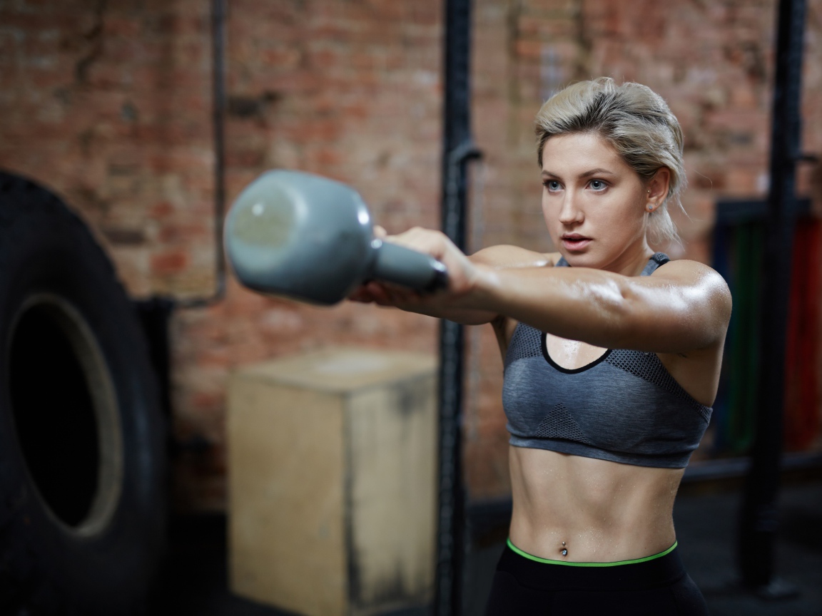 Спортивная девушка с гантелей в спортзале