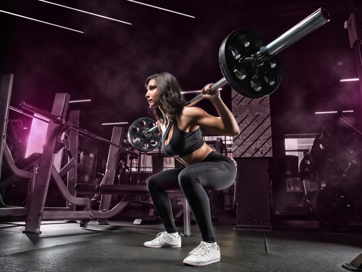 Weightlifter girl lifts the barbell in the gym