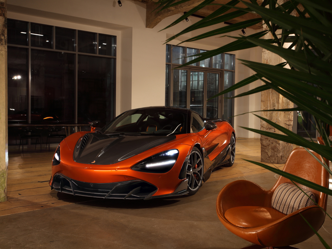 Оранжевый автомобиль  McLaren 720S у дома с креслом