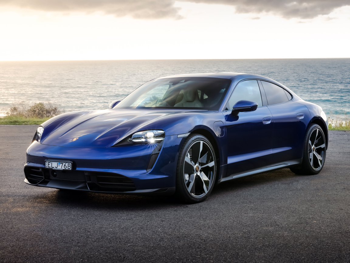 Синий автомобиль Porsche Taycan Turbo у моря