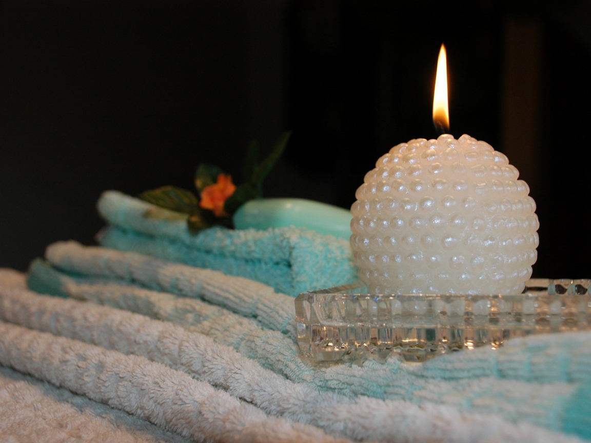 Красивая зажженная свеча с полотенцами