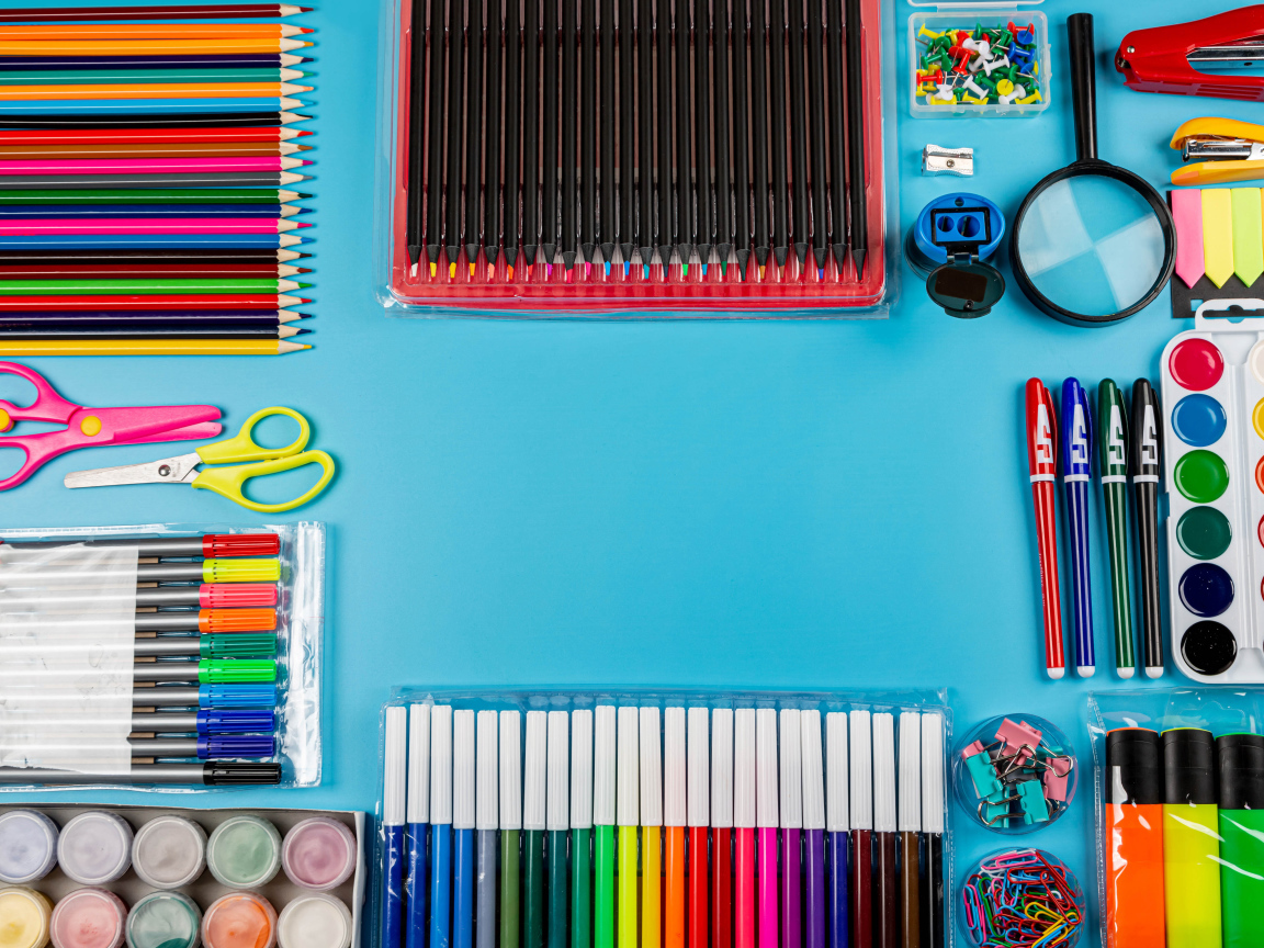 Много разноцветных канцелярских предметов на голубом фоне 