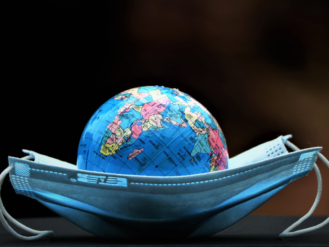 Медицинская маска и глобус на черном фоне