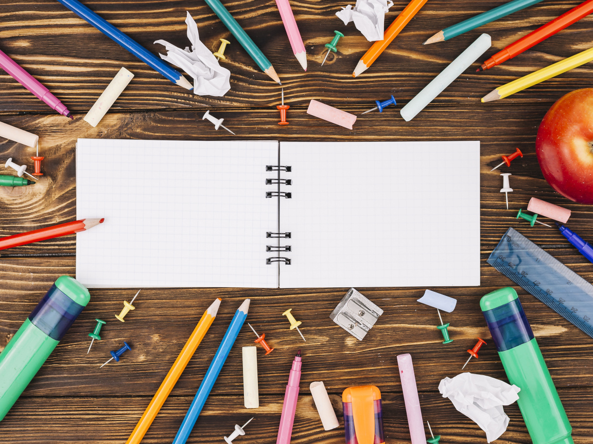 Открытый блокнот с ручками  на столе 