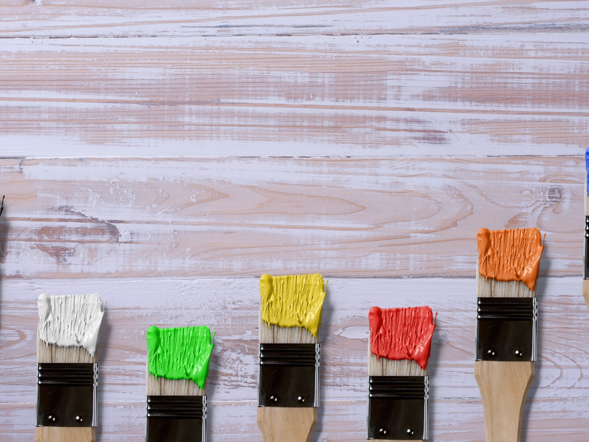 Кисточки в краске на деревянном фоне