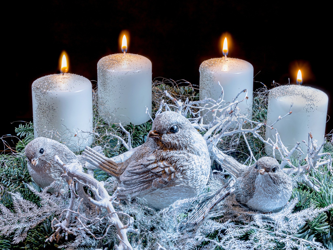 Три зажженные свечи со статуэтками птицами 