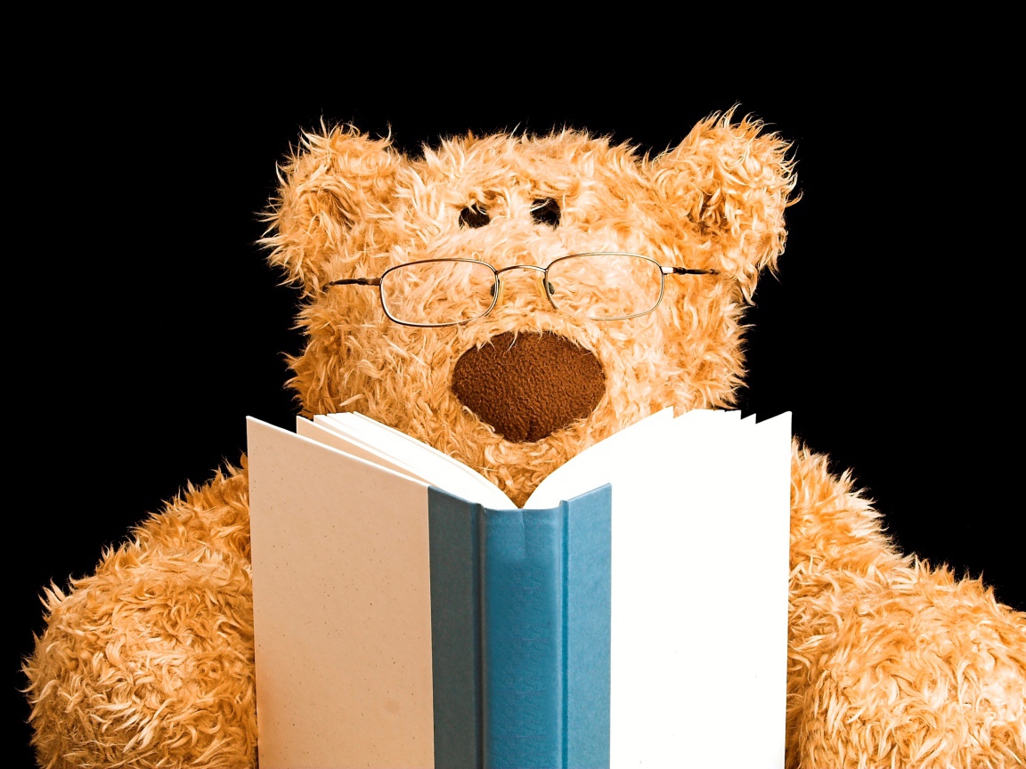 Игрушечный медведь в очках с книгой на черном фоне