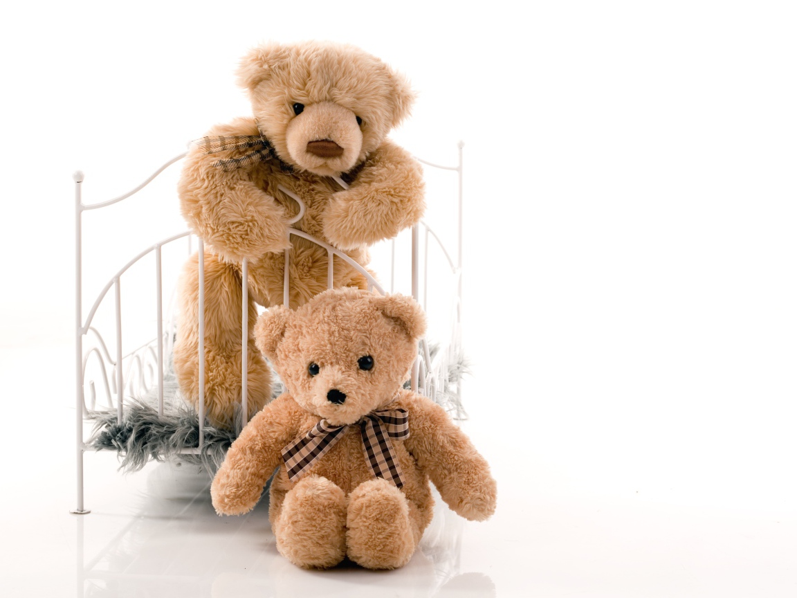 Два игрушечных медведя с кроватью на белом фоне 