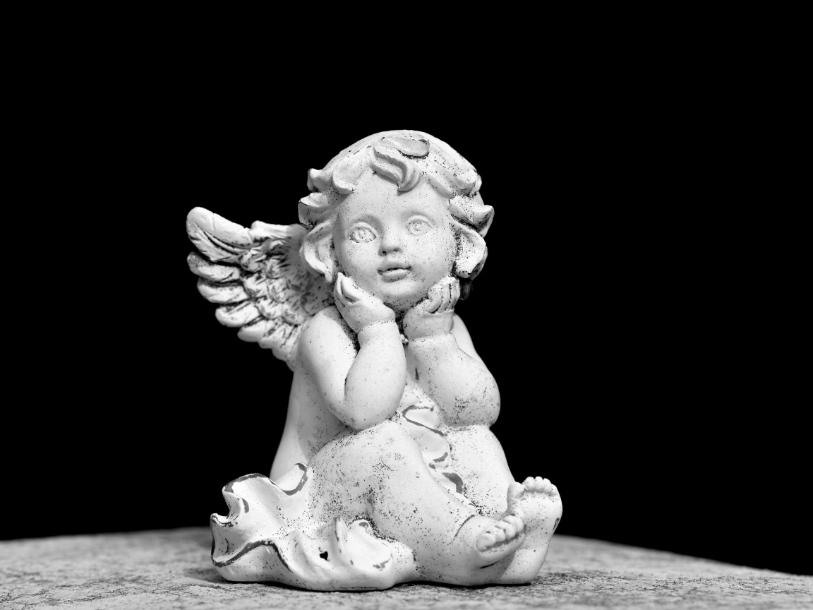 Белая статуэтка ангел на черном фоне