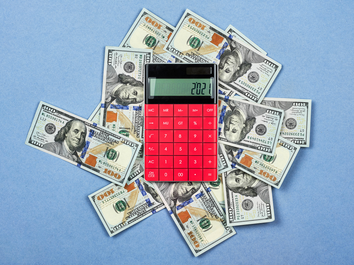Много долларов с калькулятором на синем фоне