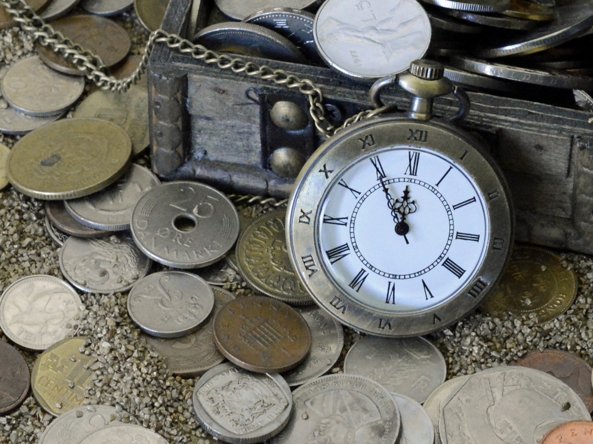 Много монет и карманные часы на песке