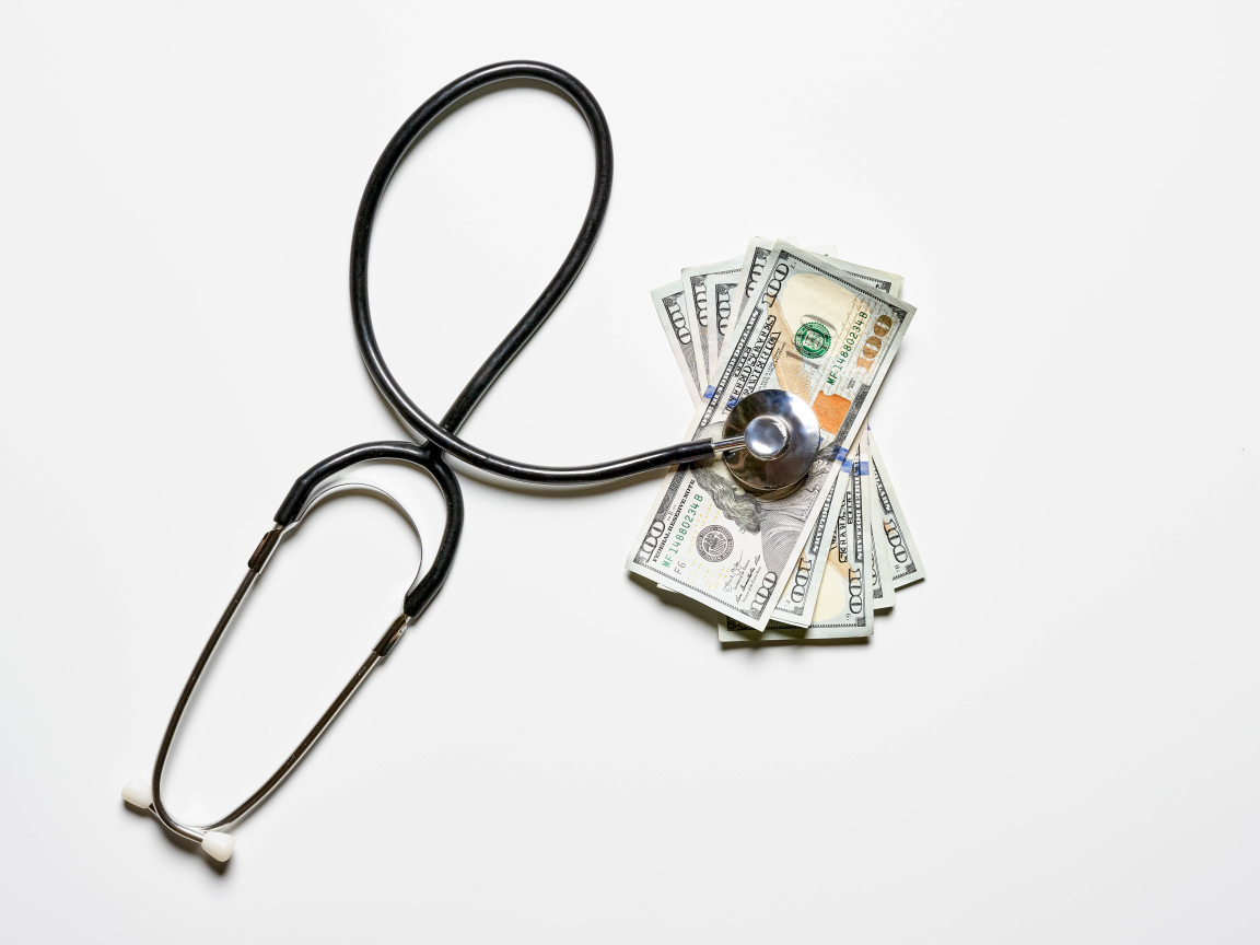 Фонендоскоп с долларами на белом фоне