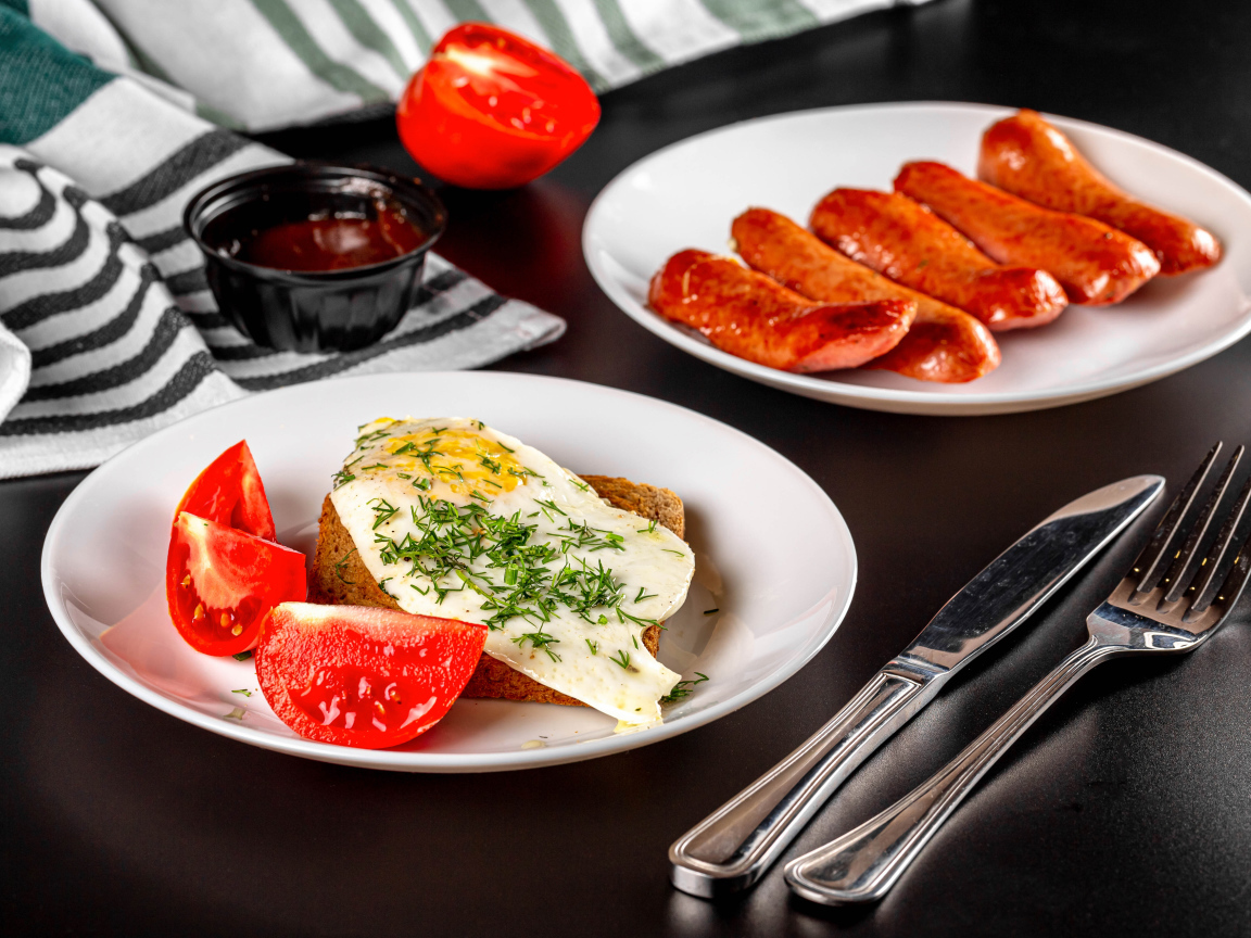 Хлеб с яичницей и помидорами на тарелке с сосисками