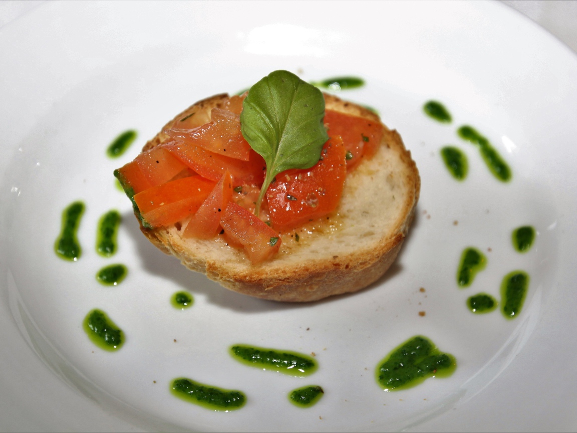 Брускетта на тарелке с помидорами и соусом