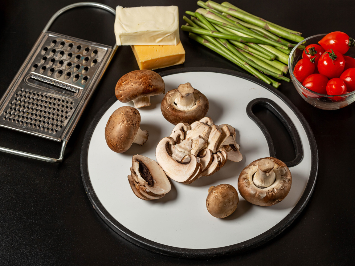 Шампиньоны на столе со спаржей и помидорами 