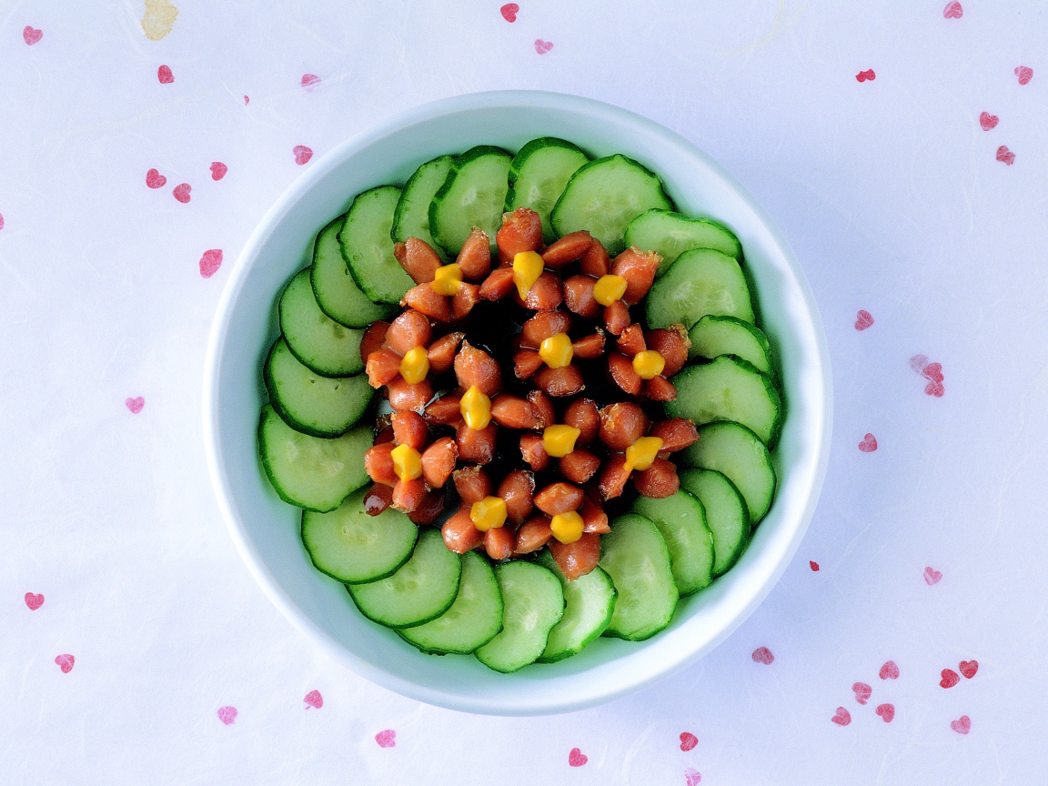 Огурцы с сосисками в тарелке на столе